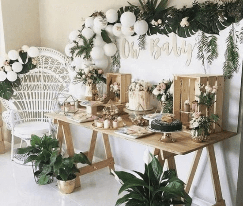 Boho Baby Shower Table setting showing a white, gold and sage green coloured set up, palm leaves, white balloons and gold cutlery that complements the theme