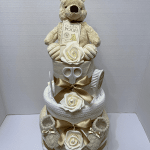 Woodland Bear Nappy Cake with 3 tiers of blankets and muslin squares in a cream and white colourway, practical baby products and a Winnie the Pooh soft toy on top