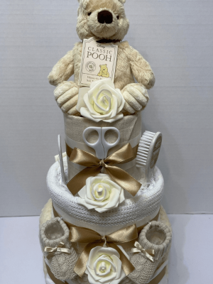 Woodland Bear Nappy Cake with 3 tiers of blankets and muslin squares in a cream and white colourway, practical baby products and a Winnie the Pooh soft toy on top