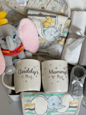 Dumbo elephant baby hamper filled with a toy, clothing set, muslins and mum and dad mugs
