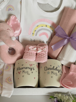 Pink rainbow baby hamper, contains baby clothing set with rainbow motif, muslin squares, booties and soft toy with mum and dad mugs