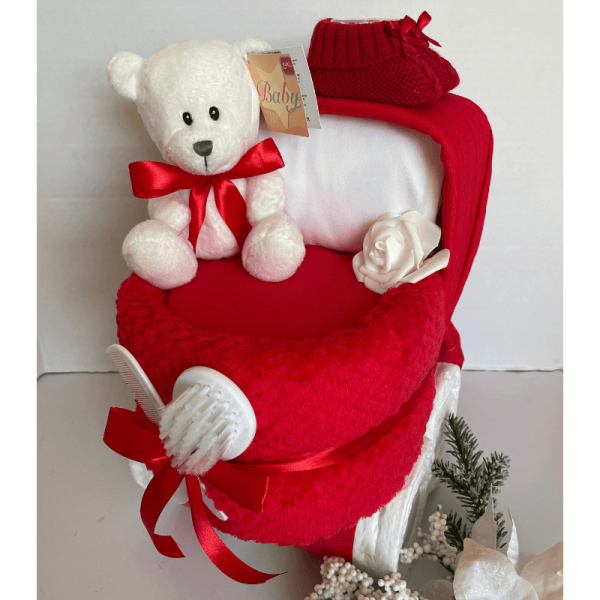 Nappy Cake Pram Red, a baby gift in the shape of a pram that is curated from practical baby products and includes a white baby 1st bear.